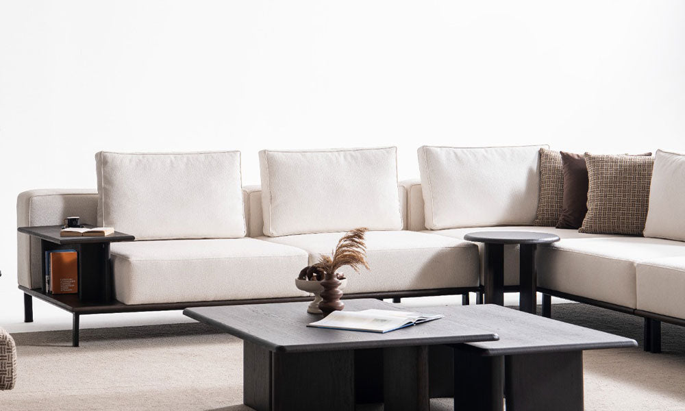 Arinna Köşe Takımı'nın modüler parçalarının birleşimi ve modüller arasına entegre edilmiş koyu renkli yan sehpa detayının yakın çekimi.