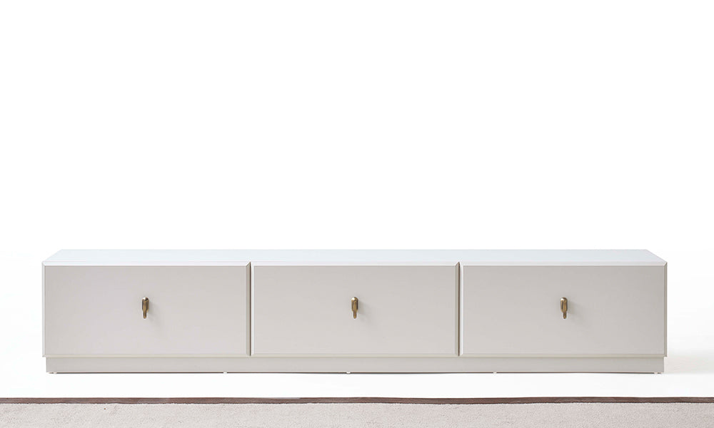 Asel Modern TV Ünitesi önden görünüm; yere sıfır ipeksi mat beyaz gövde, üç geniş depolama alanı ve şampanya renkli dikey metal kulplar.