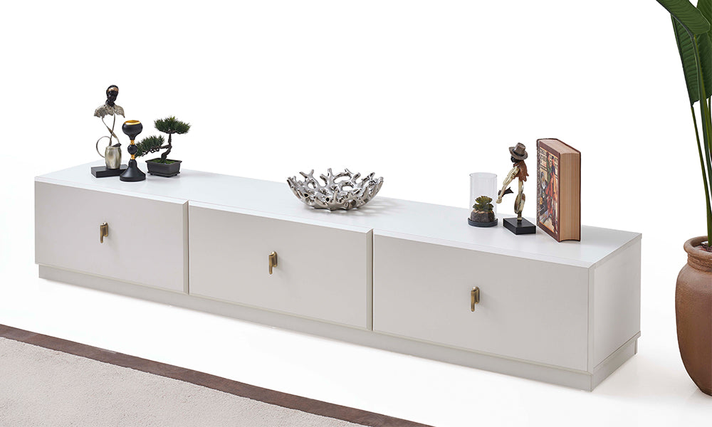 Asel Modern TV Ünitesi önden görünüm; yere sıfır ipeksi mat beyaz gövde, üç geniş depolama alanı ve şampanya renkli dikey metal kulplar.