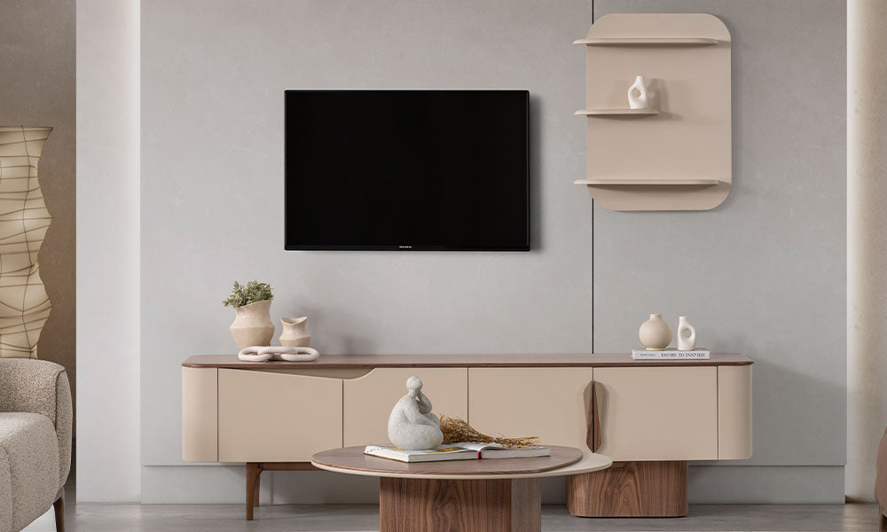 Aura Modern TV sehpası; mat bej lake yüzey, ceviz detaylar ve duvara monte oval hatlı minimalist raf modülü ile oturma odası yerleşimi.