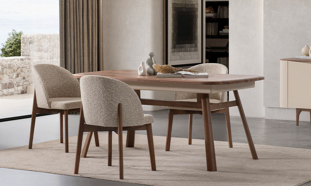 Aura Modern Yemek Masası'nın oval köşeli ceviz üst tablası, bej boyalı ahşap ayakları ve bukle kumaş sandalyelerle modern yemek odası yerleşimi.