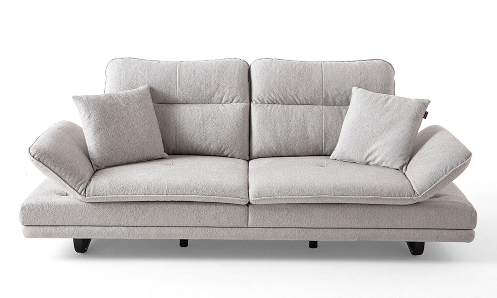 Açık gri renkli Fiesta Modern üçlü koltuğun genişletilmiş oturum alanı ve hareketli kolçaklarıyla konforlu stüdyo duruşu.