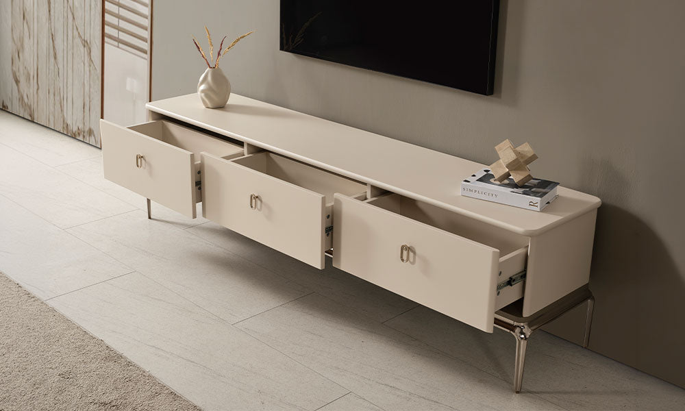 Krem modern TV ünitesinin açık üç geniş çekmecesi, metal ray sistemi, oval kulpları ve dekoratif üst tablası.