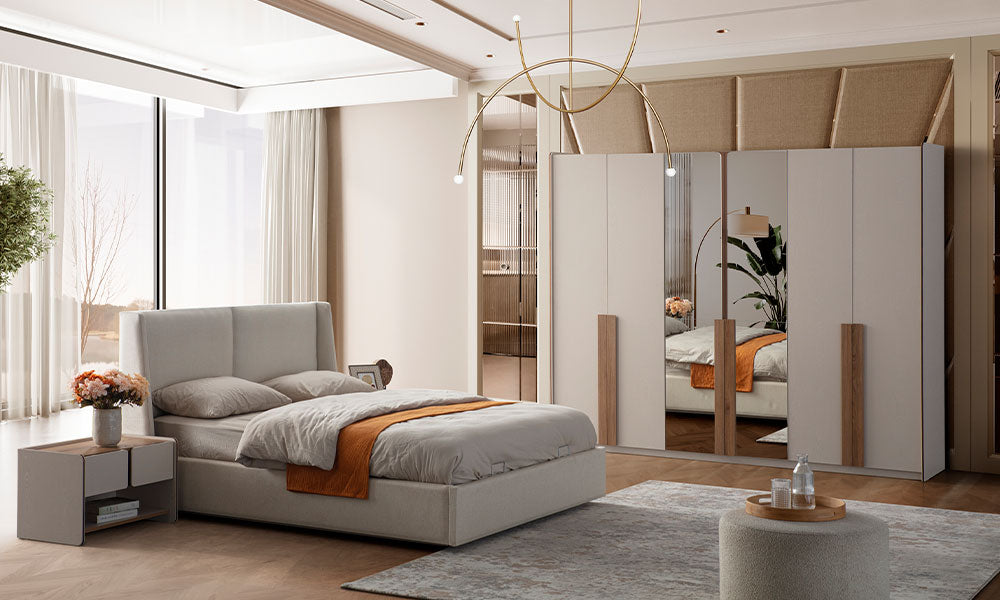 İznik Modern yatak odasında, kumaş başlıklı bazalı karyola ve altı kapaklı, aynalı, ahşap kulplu gardırobun şık görünümü.