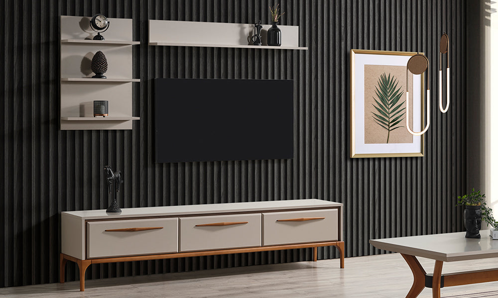 Kumsal modern TV ünitesi; krem renkli üç çekmeceli alt modül, duvar rafları ve ahşap ayak detaylarıyla salon ortamında