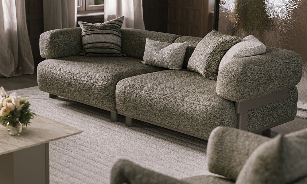 Mocha Modern üçlü koltuğun metal baza detayını, geniş oturum alanını ve zengin kumaş dokusunu gösteren şık salon duruşu.