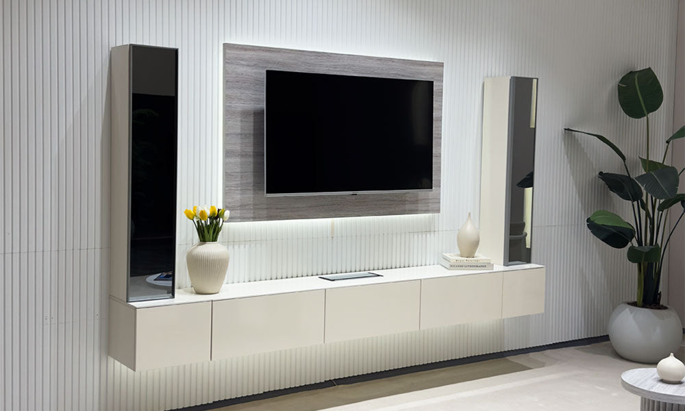 Uçan TV Ünitesi'nin aytaşı rengi düz TV paneli ve ortası aynalı konsol modülü, koyu renk yivli duvar önünde.