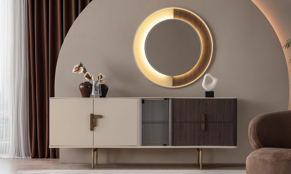 Modern bir salonda, Velar koleksiyonuna ait asimetrik tasarımlı konsol, çekmeceler, cam kapak ve altın metal ayak detayları.