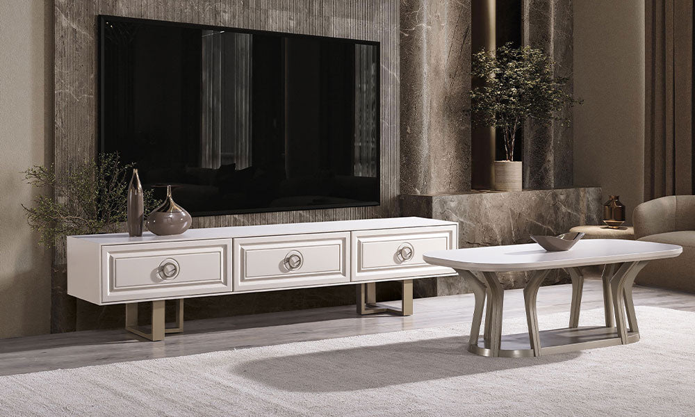 Alkan Modern TV Ünitesi; krem rengi çerçeve detaylı 3 çekmeceli gövde, bronz halka kulplar, geometrik gold ayaklar ve mermer duvarlı lüks salon dekorasyonu.