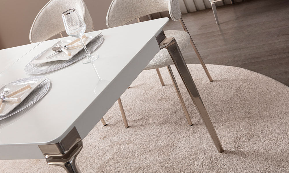 Bronz beyaz yemek masasının yuvarlatılmış tabla köşesi, metal ayağı ve açık renk döşemeli sandalyeleri