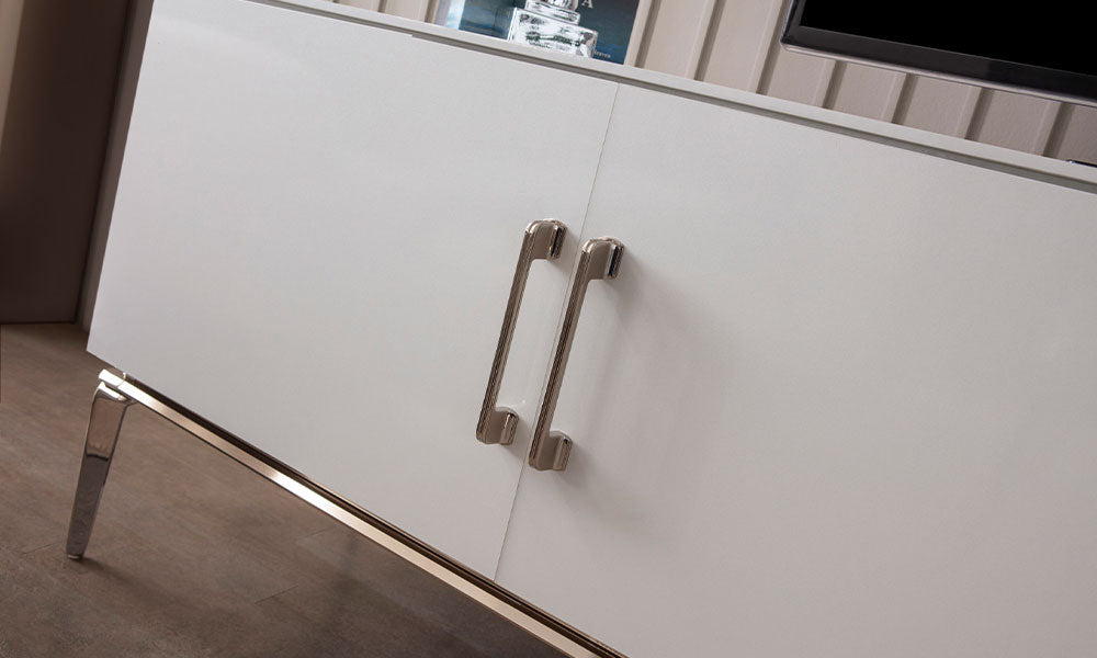 Bronz Modern TV Ünitesinin beyaz kapakları, uzun metal kulpları ve bronz renkli yüksek ayak detayları