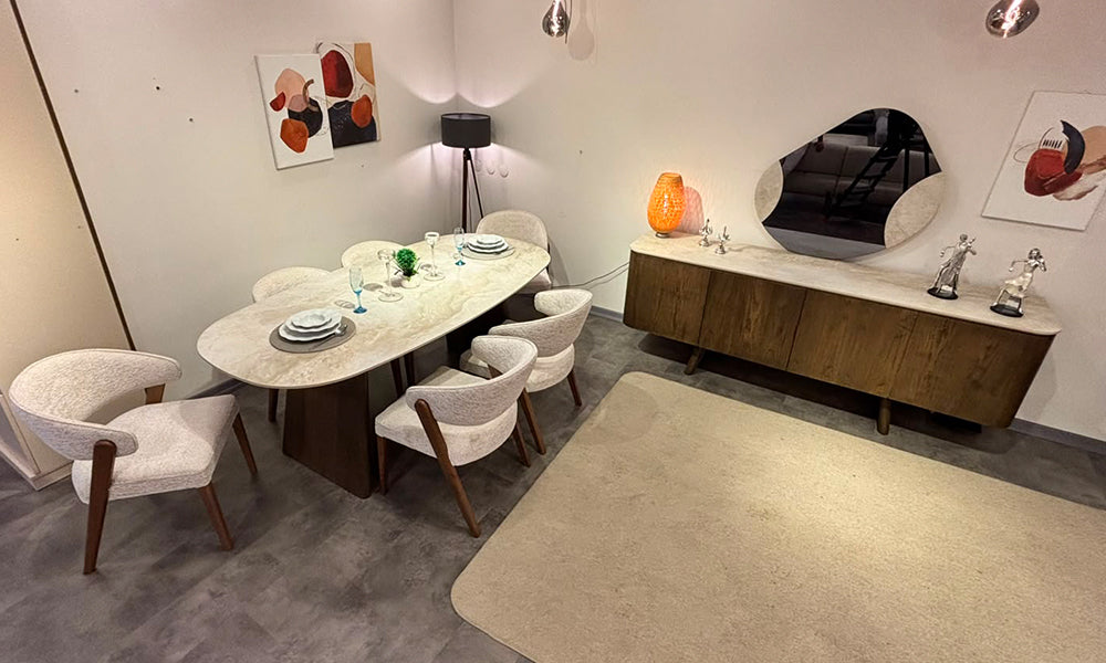 alista modern seramik yemek odası takımı salon yerleşimi; ısıya dayanıklı oval seramik masa, ahşap konsol ve açık renk ergonomik kumaş sandalyeler.