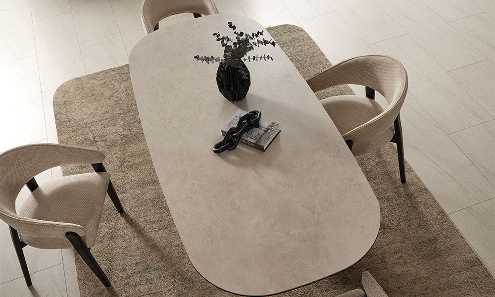 Cartier Modern Seramik Yemek Masası, açık renkli oval tabla ve krem sandalyelerle üstten görünüm
