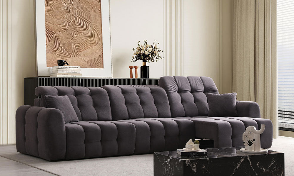 Antrasit renkli Enzo Modern dörtlü koltuğun kapitoneli tasarımının ve puf kollarının lüks bir salondaki yandan görünümü.