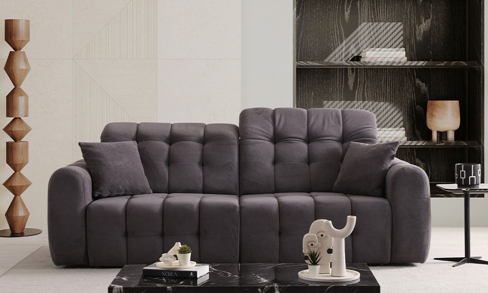 Enzo Modern üçlü koltuğun kapitoneli ve puf tasarımlı, antrasit renkli, modern bir salondaki önden görünümü.