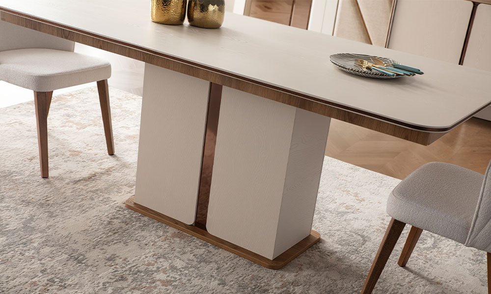 İznik Modern yemek masasının iki panelli mimari ayak yapısının ve metalik/ahşap bordürlü bej tablasının yakın çekim detayı.
