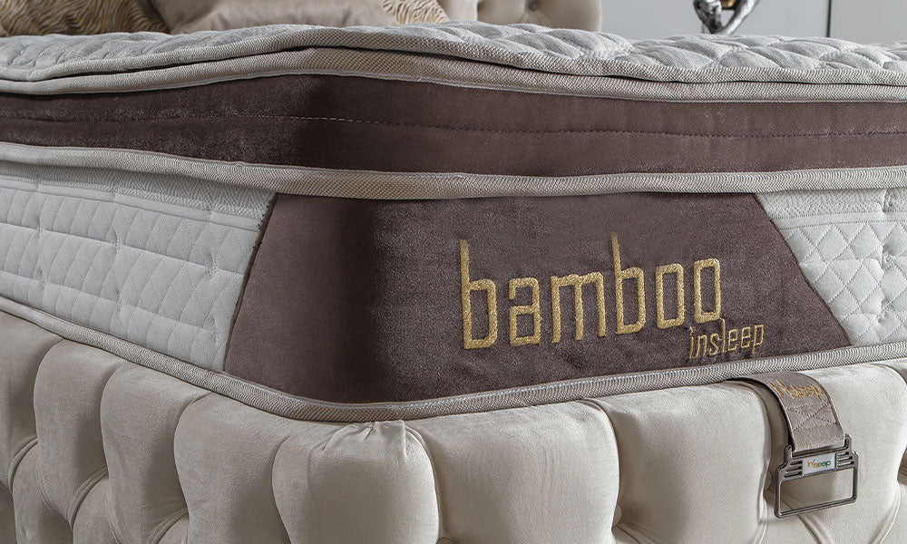Lamore modern baza başlık setindeki Bamboo yatağın kahverengi biye, kapitone kumaş ve marka detayının yakın görünümü