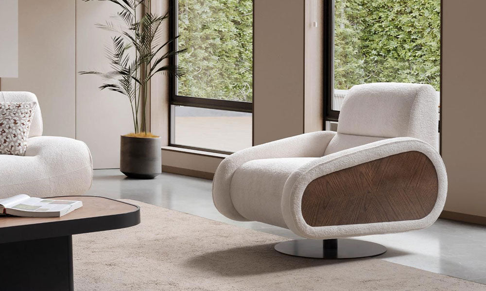 Krem kumaşlı Alfa modern berjer, oval ahşap kol detayı, ergonomik sırt yapısı ve döner metal tabanıyla pencere önünde.