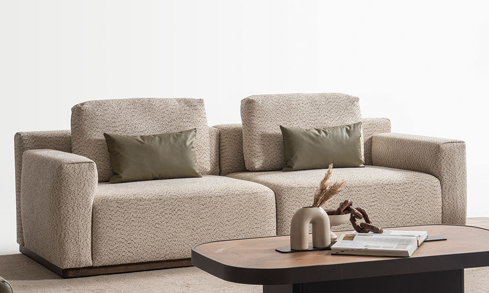 Mengen Modern Üçlü Koltuk'un bukle dokulu bej kumaş kaplı, iki modülden oluşan sade ve deep-seating konforlu görünümü; zeytin yeşili deri kırlent detayı.