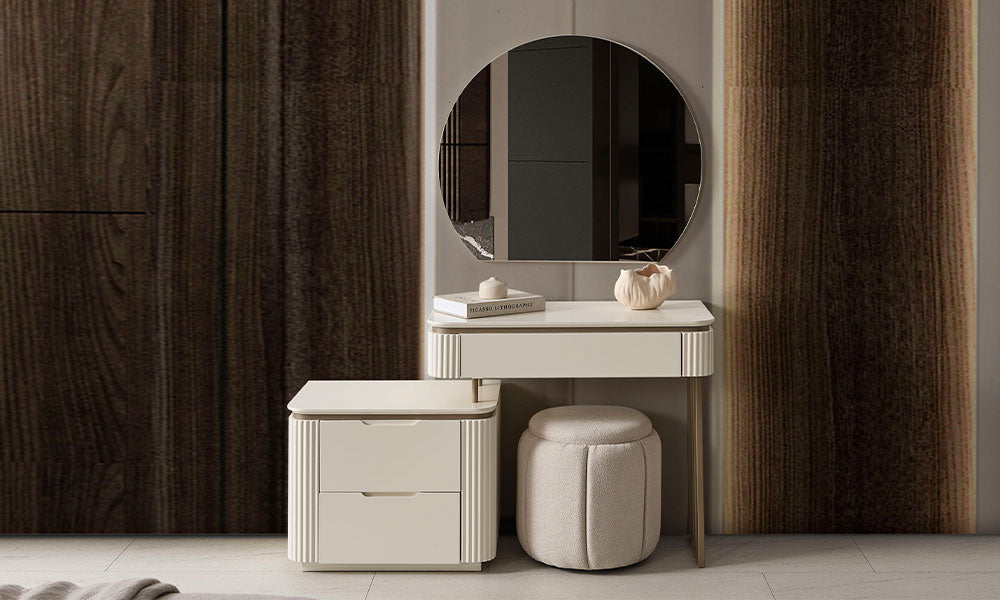 New Golden modern şifonyer takımı; dikey yivli krem renkli ön yüzeylere, gold kulplara ve yüksek gold metal ayaklara sahip geniş şifonyer, uzun boy şifonyer (tallboy) ve duvar aynasının lüks bir yatak odasındaki mermer duvar önünde tam takım görünümü.