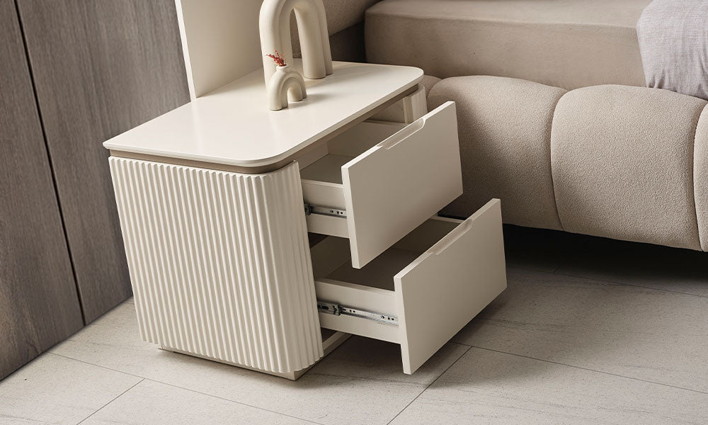 Yatak odası için modern tasarımlı, krem renkli dikey yivli gövdeli ve yüksek gold metal ayaklı New Golden komodinin yandan profilden görünümü.