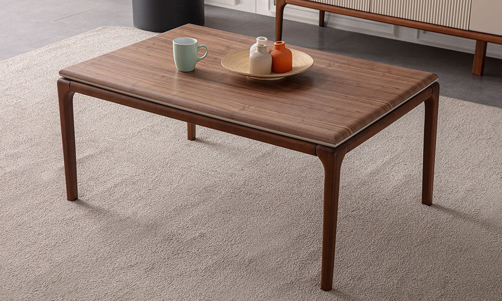 New Rivas Modern Orta Sehpa'nın ceviz rengi dikdörtgen üst tablası, yuvarlatılmış güvenli köşeleri ve zarif konik ahşap ayakları ile halı üzerindeki görünümü.