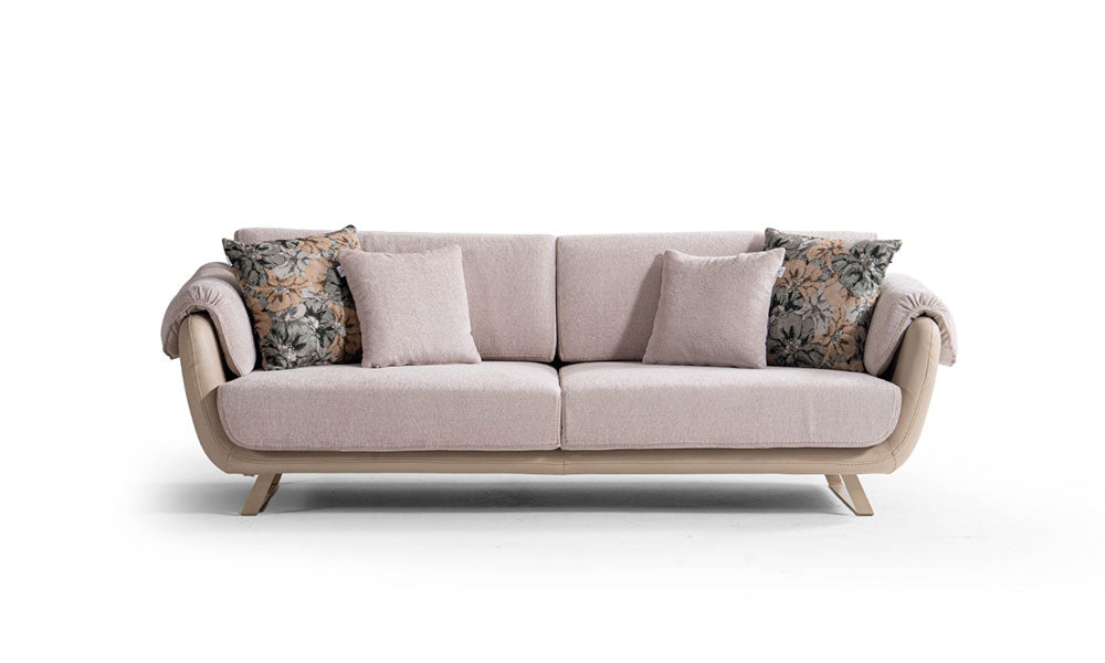 Pudra renkli Olivia modern üçlü koltuk, floral desenli kırlentleri, kıvrımlı kol yapısı ve metal ayaklarıyla beyaz fonda.