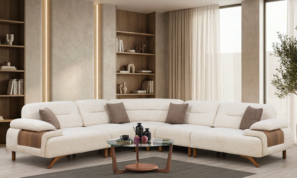 Modern salonda Petra krem köşe koltuk takımı, kavisli köşe modülü, ahşap kol detayları ve dekoratif kırlentler
