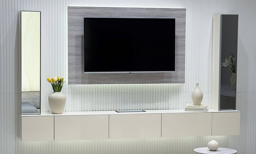 Uçan TV Ünitesi'nin aytaşı rengi düz TV paneli ve ortası aynalı konsol modülü, koyu renk yivli duvar önünde.