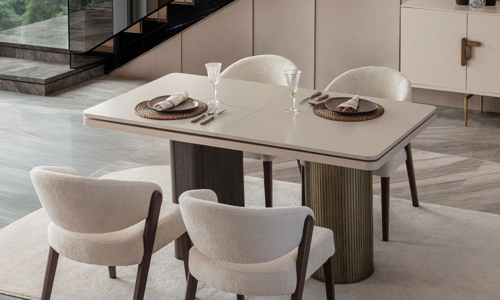 Beyaz arka planda, Velar Modern yemek masasının açılır tablası, koyu ahşap paneli ve yivli metalik silindir ayağından oluşan asimetrik tasarımı.